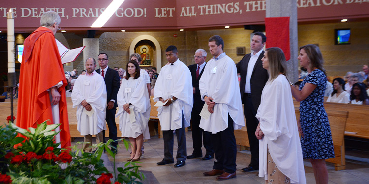 Adult members stand around altar in front of pastor