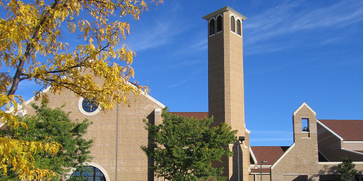 Exterior of Saint Francis church; tree with yellow leaves partially covers.