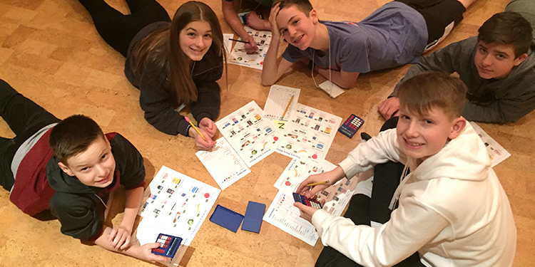 Group of teens laying on the floor in a circle working on homework