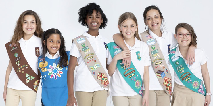 Six girl scouts wearing sashes and badges smile for photo