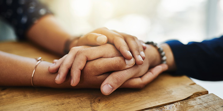 Two people holding hands across a wooden table