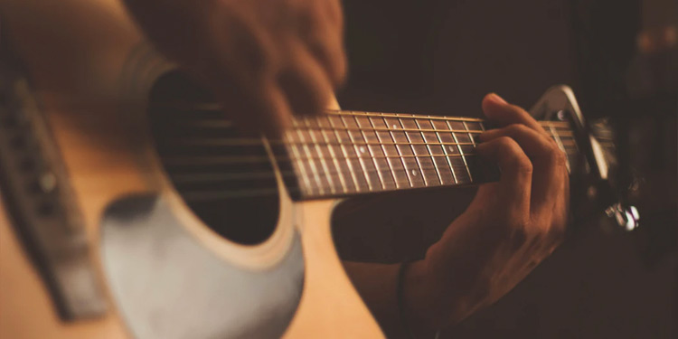 Closeup on hands playing an acoustic guitar