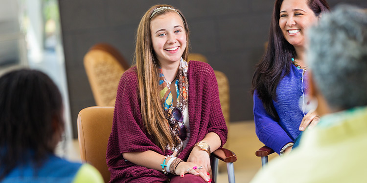 Women sit in a circle smiling and talking